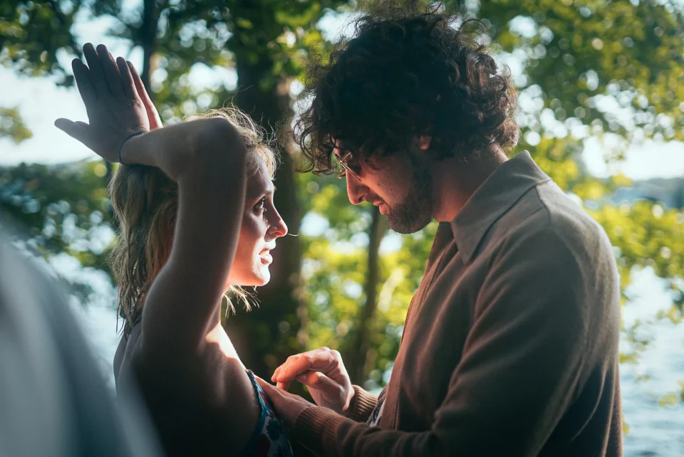 Two people talking in dappled outdoor light.