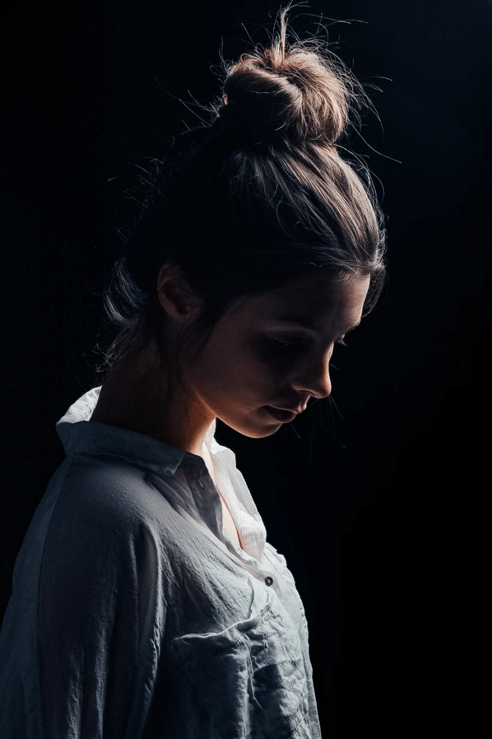 A portrait in profile, with a high bun and soft side lighting.
