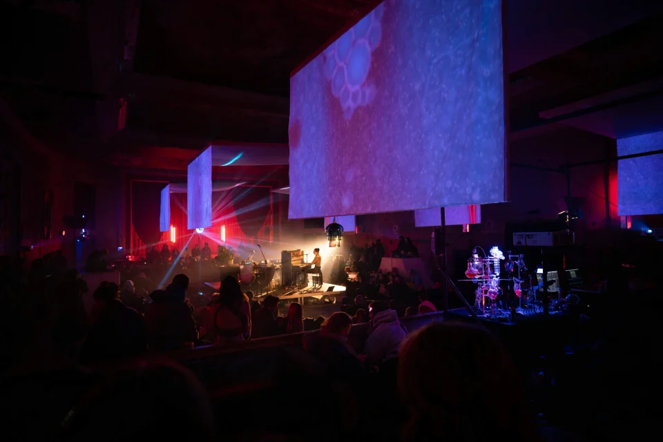 An audience gathers around a piano beneath suspended microscopic projections in the historic Wilhelmine hall.