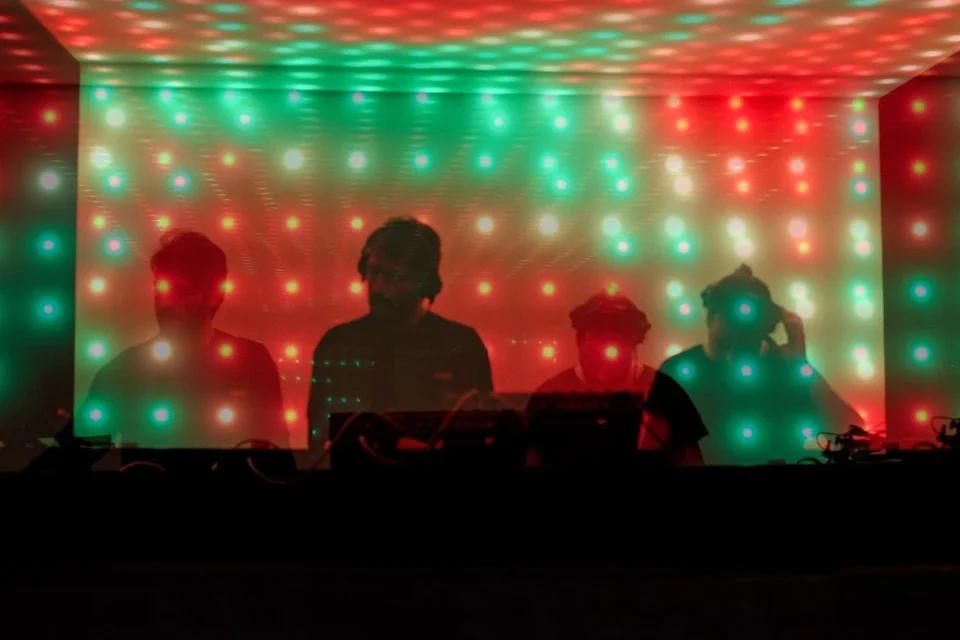 Performers silhouetted against reflected green and red LED lights at Watergate.