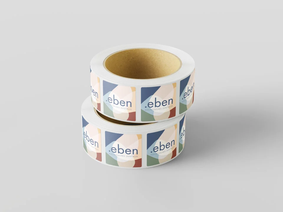 Two stacked rolls of eben packaging labels with colourful abstract graphics and fine typography.