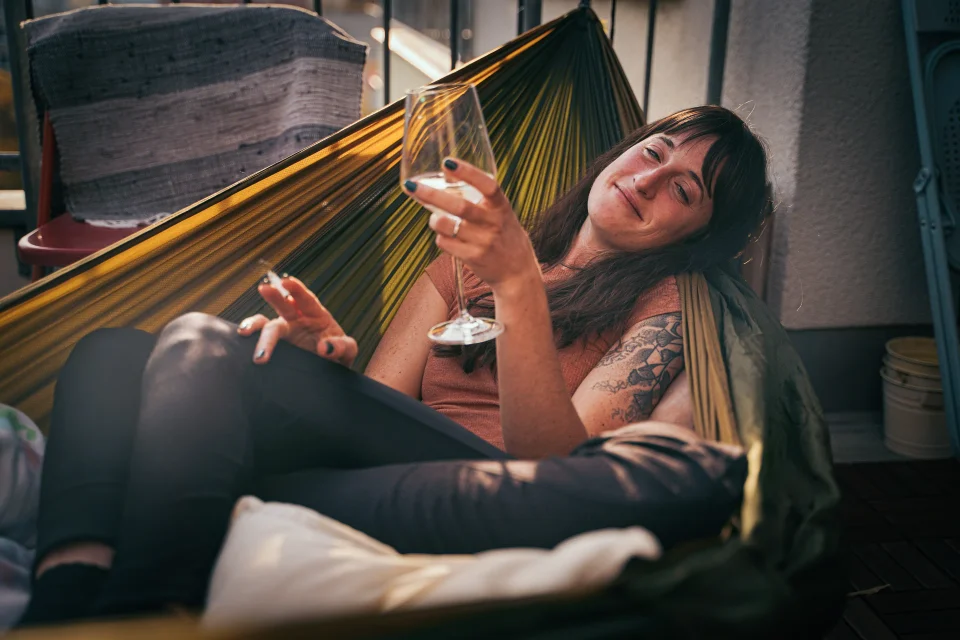 A person rests in a striped hammock.