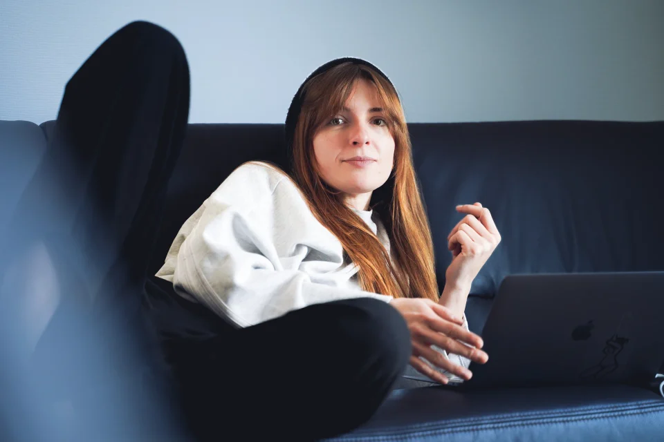 A person seated on a sofa in directional afternoon light.