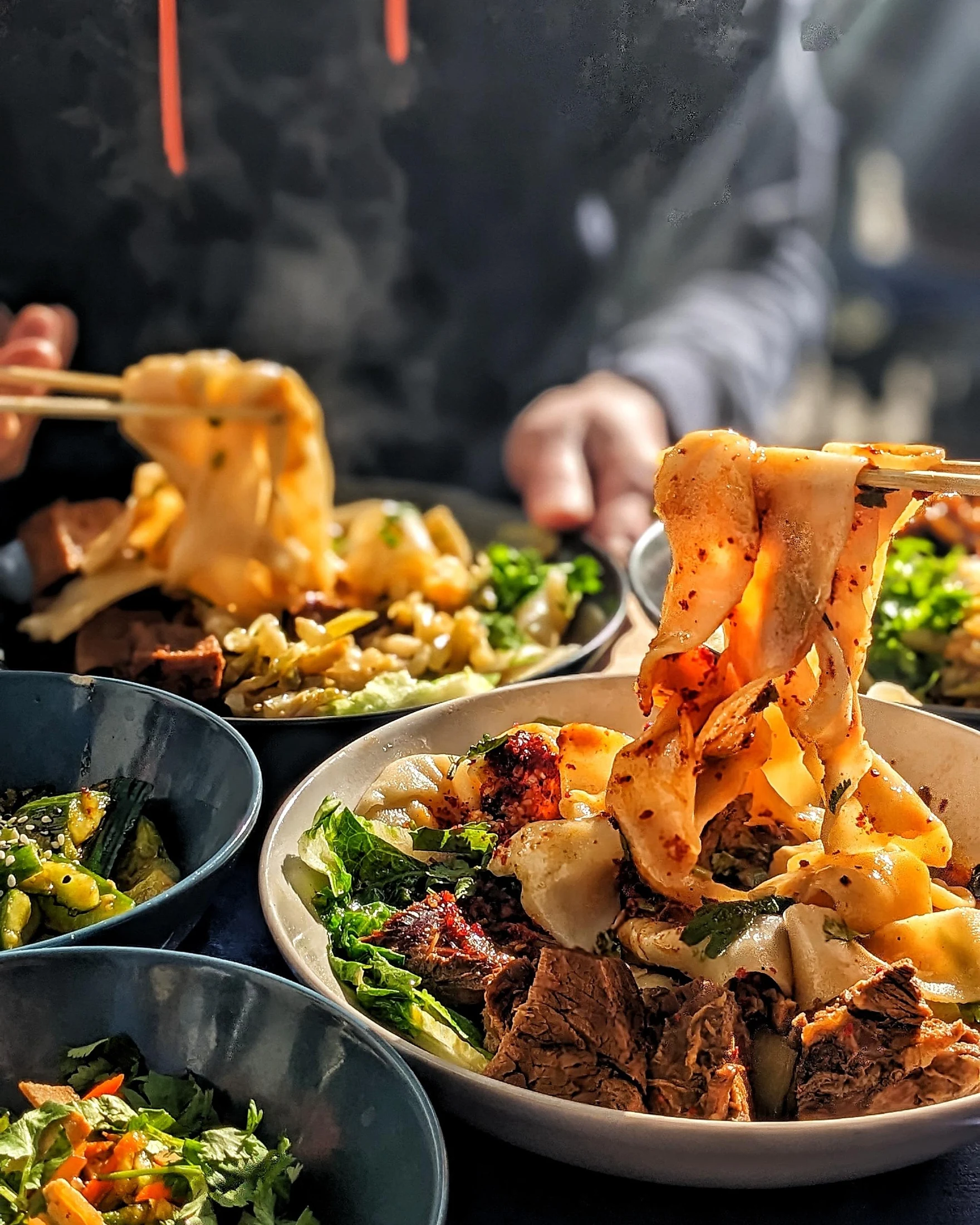 Hand-pulled noodles lifted from steaming bowls at a shared Wen Cheng table.